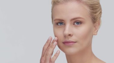 Cilt bakımı kremi süren genç, güzel ve doğal sarışın kadının stüdyo portresi. Yüz gerdirme, kozmetik ve makyaj konsepti.