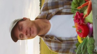 Farmer with a vegetable box in front of a sunset agricultural landscape. Man in a countryside field. The concept of country life, food production, farming and country lifestyle.