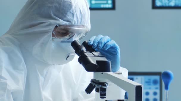 研究室の機器を使用して研究室で働く保護スーツとマスクの科学者 顕微鏡 試験管 技術のコンセプト — ストック動画