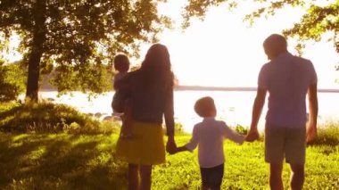 Deniz kenarında mutlu bir aile. Kırsal kesimde tarla ve ağaçlar. Gün batımının ya da güneşin sıcacık renkleri. Sevgi dolu ebeveynler ve güzel çocuklar. Aşk ve ebeveynlik kavramı.