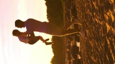 Deniz kenarında mutlu bir aile. Kırsal kesimde tarla ve ağaçlar. Gün batımının ya da güneşin sıcacık renkleri. Sevgi dolu ebeveynler ve güzel çocuklar. Aşk ve ebeveynlik kavramı.