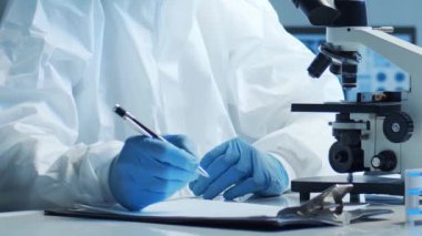 Laboratuvar ekipmanları, mikroskoplar ve test tüpleri kullanarak araştırma laboratuarında çalışan koruyucu giysi ve maskeler giyen bilim adamları. Tıp, sağlık ve teknoloji kavramı.