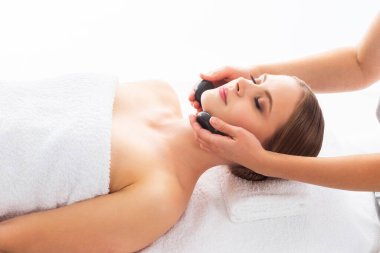Beyaz arka planda masaj yaptıran genç bir kadın. Spa, sağlık ve dinlenme konsepti.