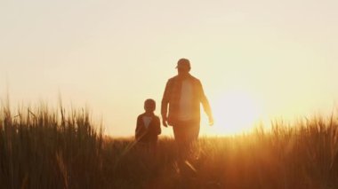 Çiftçi ve oğlu gün batımında tarım arazisinde yürüyorlar. Kırsalda bir adam ve bir çocuk. Babalık kavramı, köy hayatı, tarım ve kırsal yaşam tarzı..