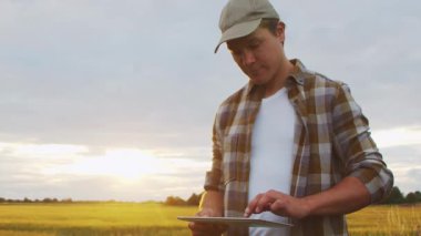 Günbatımı tarımının önündeki çiftçi. Kırsal kesimde bir adam. Kır hayatı, gıda üretimi, tarım ve kırsal yaşam tarzı kavramı.