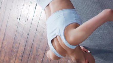 Spor giyimli genç ve sportif kız evde egzersiz yapıyor. Formda ve narin sarışın kadın spor ve spor için geliyor. Sağlık sigortası, yağ yakma ve sağlık konsepti. Dikey video.