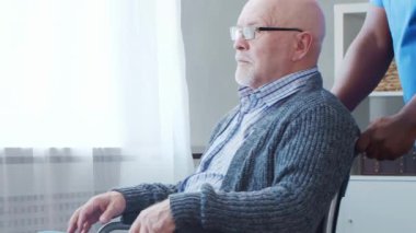 Afro-Amerikalı bakıcı ve yaşlı adam. Bakımevindeki profesyonel hemşire ve hastası. Yardım, rehabilitasyon ve sağlık hizmetleri kavramı.