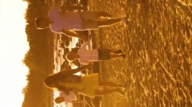 Deniz kenarında mutlu bir aile. Kırsal kesimde tarla ve ağaçlar. Gün batımının ya da güneşin sıcacık renkleri. Sevgi dolu ebeveynler ve güzel çocuklar. Aşk ve ebeveynlik kavramı.