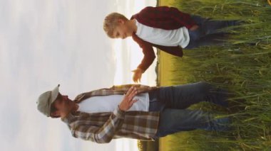 Çiftçi ve oğlu gün batımında tarım alanında el sıkışıyorlar. Kırsalda bir adam ve bir çocuk. Babalık kavramı, köy hayatı, tarım ve kırsal yaşam tarzı..