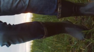 Çimenlerde yürüyen çizmeli bir çiftçi. Kırsal kesimde bir adam. Kır hayatı, gıda üretimi, tarım ve kırsal yaşam tarzı kavramı.