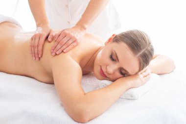 Beyaz arka planda masaj yaptıran genç bir kadın. Spa, sağlık ve dinlenme konsepti.