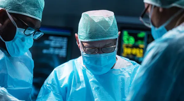 Разнообразная Команда Профессиональных Врачей Проводит Хирургическую Операцию Современной Операционной Использованием Стоковое Изображение