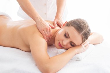 Beyaz arka planda masaj yaptıran genç bir kadın. Spa, sağlık ve dinlenme konsepti.