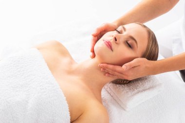 Beyaz arka planda masaj yaptıran genç bir kadın. Spa, sağlık ve dinlenme konsepti.