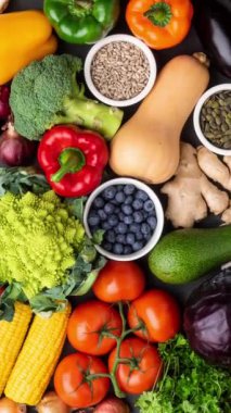 Dikey video. Sağlıklı yiyecekler: taze sebzeler, meyveler ve süper yiyecekler. Beslenme, diyet, vejetaryen gıda konsepti. Siyah arkaplan