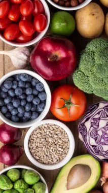 Dikey video. Sağlıklı yiyecekler: taze sebzeler, meyveler ve süper yiyecekler. Beslenme, diyet, vejetaryen gıda konsepti. Siyah arkaplan