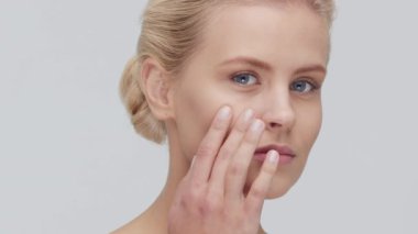 Cilt bakımı kremi süren genç, güzel ve doğal sarışın kadının stüdyo portresi. Yüz gerdirme, kozmetik ve makyaj konsepti.