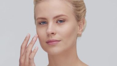 Cilt bakımı kremi süren genç, güzel ve doğal sarışın kadının stüdyo portresi. Yüz gerdirme, kozmetik ve makyaj konsepti.