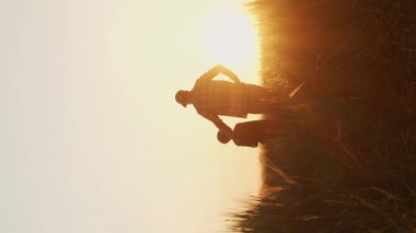 Çiftçi ve oğlu günbatımı tarımının önünde. Kırsalda bir adam ve bir çocuk. Babalık kavramı, köy hayatı, çiftçilik ve kırsal yaşam tarzı. Dikey video.