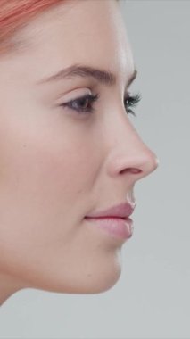 Cilt bakımı kremi süren genç, güzel ve doğal kızıl saçlı kadının stüdyo portresi. Yüz gerdirme, kozmetik ve makyaj konsepti. Dikey video.