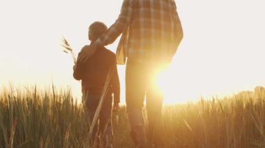 Farmer and his son in front of a sunset agricultural landscape. Man and a boy in a countryside field. The concept of fatherhood, country life, farming and country lifestyle.