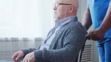 Afro-Amerikalı bakıcı ve yaşlı adam. Bakımevindeki profesyonel hemşire ve hastası. Yardım, rehabilitasyon ve sağlık hizmetleri kavramı.