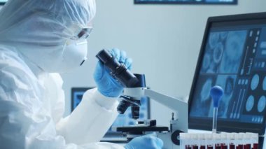 Laboratuvar ekipmanları, mikroskoplar ve test tüpleri kullanarak araştırma laboratuarında çalışan koruyucu giysi ve maskeler giyen bilim adamları. Tıp, sağlık ve teknoloji kavramı.