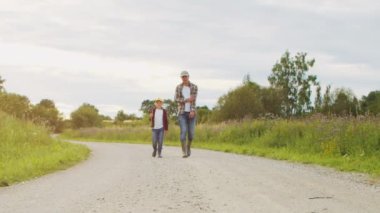 Çiftçi ve oğlu günbatımı tarımının önünde. Kırsalda bir adam ve bir çocuk. Babalık kavramı, köy hayatı, tarım ve kırsal yaşam tarzı..