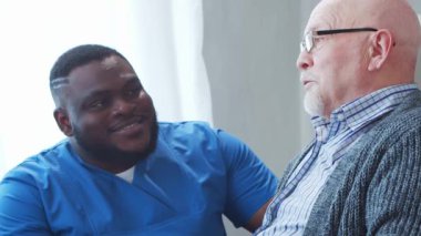 Afro-Amerikalı bakıcı ve yaşlı adam. Bakımevindeki profesyonel hemşire ve hastası. Yardım, rehabilitasyon ve sağlık hizmetleri kavramı.