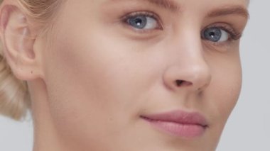 Yüzüne nazikçe masaj yapan genç, güzel ve doğal sarışın kadının stüdyo portresi. Yüz gerdirme, kozmetik ve makyaj konsepti.