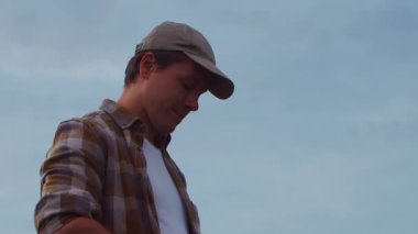 Günbatımı tarımının önündeki çiftçi. Kırsal kesimde bir adam. Kır hayatı, gıda üretimi, tarım ve kırsal yaşam tarzı kavramı.