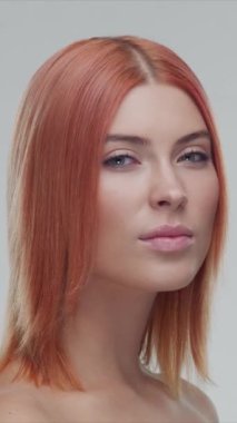 Stüdyo portresi, genç, güzel ve doğal kızıl saçlı kadın pozu. Yüz gerdirme, kozmetik ve makyaj konsepti. Dikey video.