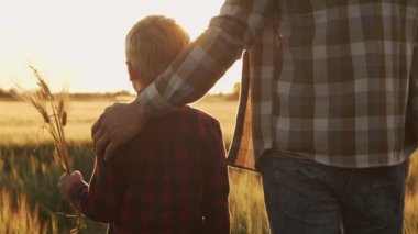 Çiftçi ve oğlu günbatımı tarımının önünde. Kırsalda bir adam ve bir çocuk. Babalık kavramı, köy hayatı, tarım ve kırsal yaşam tarzı..