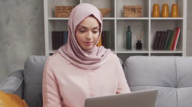 Türbanlı ve koruyucu maskeli genç Müslüman kızın yakın plan portresi. Üzgün Orta Doğulu kadın evde kameranın önünde oturuyor. Yakın plan..