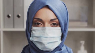 Hastane ofisinde çalışan profesyonel tıp doktoru koruyucu maskeli genç ve çekici bir kadın doktorun portresi. Tıbbi video konsepti.