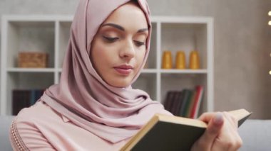 Türbanlı ve koruyucu maskeli genç Müslüman kızın yakın plan portresi. Üzgün Orta Doğulu kadın evde kameranın önünde oturuyor. Yakın plan..