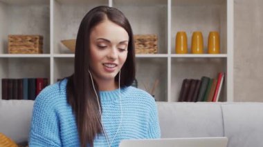 Genç ve çekici bir kadın evde dizüstü bilgisayar kullanarak çalışıyor. Serbest çalışan ya da öğrenci çevrimiçi konuşma yapıyor. Dikey video.