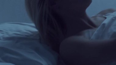 Genç bir kadın geceleri yatakta uzanıyor ve uykusuzluk hastalığına yakalanıyor. Güzel sarışın, uyuyan kız. Yatak odasında alacakaranlık, pencereden ay ışığı. Uykusuzluk, sağlık ve dinlenme konsepti. Ev