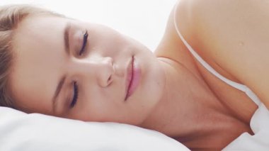 Huzurlu, huzurlu bir sahne. Genç bir kadın, rahat bir şekilde yatakta uyuyor. Yumuşak, doğal ışıklandırmayla. Rahatlama, dinlenme ve sükunet temaları için mükemmel. Ev kavramı.