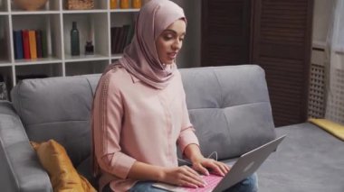 Türbanlı ve koruyucu maskeli genç Müslüman kızın yakın plan portresi. Üzgün Orta Doğulu kadın evde kameranın önünde oturuyor. Yakın plan..