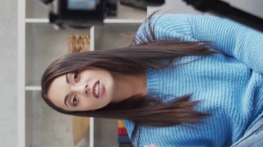 Genç ve çekici bir kadın evde dizüstü bilgisayar kullanarak çalışıyor. Serbest çalışan ya da öğrenci çevrimiçi konuşma yapıyor. Dikey video.