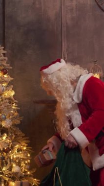 Santa Clauss atölyesi. Noel Baba masanın arkasında şömine ve Noel ağacı olan hediyesini paketlemekle meşgul. Klasik bir Noel sahnesi..