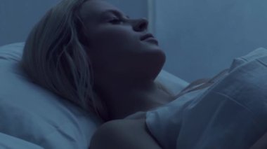 Genç bir kadın geceleri yatakta uzanıyor ve uykusuzluk hastalığına yakalanıyor. Güzel sarışın, uyuyan kız. Yatak odasında alacakaranlık, pencereden ay ışığı. Uykusuzluk, sağlık ve dinlenme konsepti. Ev