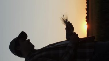Farmer in front of a sunset agricultural landscape. Man in a countryside field. The concept of country life, food production, farming and country lifestyle.