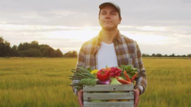 Günbatımı tarımının önündeki çiftçi. Kırsal kesimde bir adam. Kır hayatı, gıda üretimi, tarım ve kırsal yaşam tarzı kavramı.