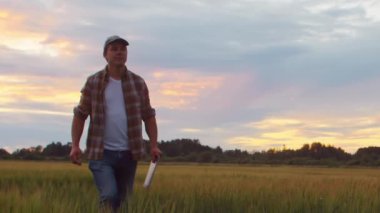 Farmer in front of a sunset agricultural landscape. Man in a countryside field. The concept of country life, food production, farming and country lifestyle.