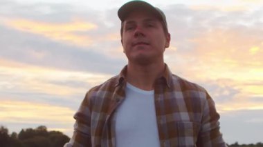 Günbatımı tarımının önündeki çiftçi. Kırsal kesimde bir adam. Kır hayatı, gıda üretimi, tarım ve kırsal yaşam tarzı kavramı.