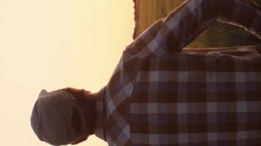 Farmer in front of a sunset agricultural landscape. Man in a countryside field. The concept of country life, food production, farming and country lifestyle.