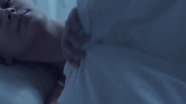 Genç bir kadın geceleri yatakta uzanıyor ve uykusuzluk hastalığına yakalanıyor. Güzel sarışın, uyuyan kız. Yatak odasında alacakaranlık, pencereden ay ışığı. Uykusuzluk, sağlık ve dinlenme konsepti. Ev