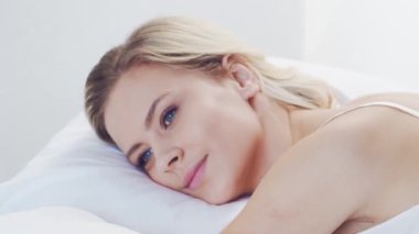 Huzurlu, huzurlu bir sahne. Genç bir kadın, rahat bir şekilde yatakta uyuyor. Yumuşak, doğal ışıklandırmayla. Rahatlama, dinlenme ve sükunet temaları için mükemmel. Ev kavramı.